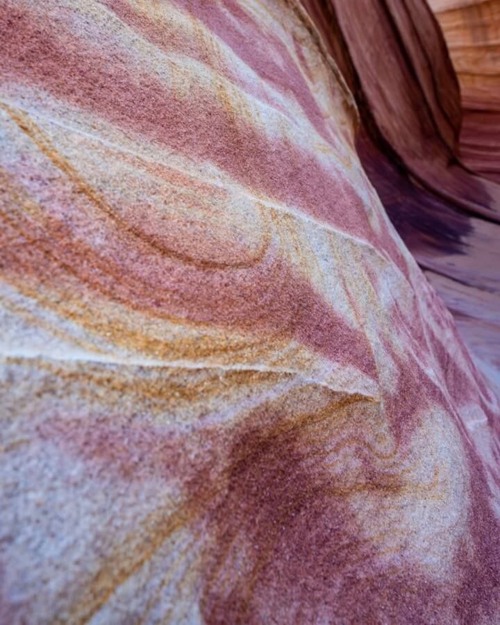 Swirling pink and yellow patterns on a sandy wall