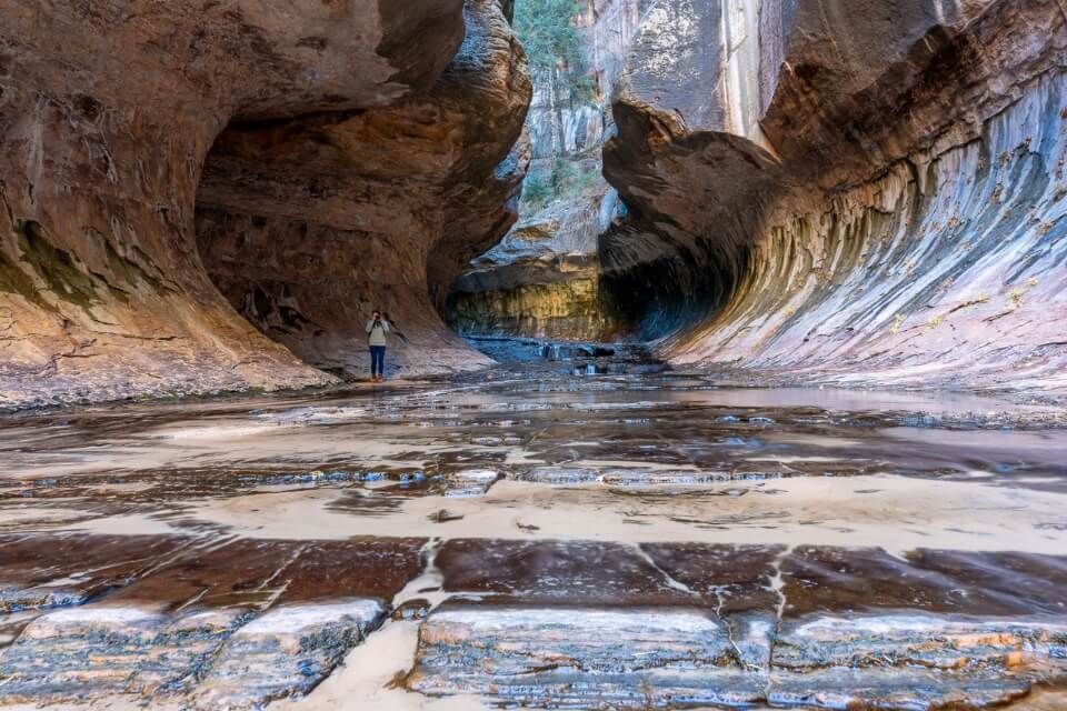 Hiker taking a photo on The Subway hike requiring permit in Zion national park in december winter