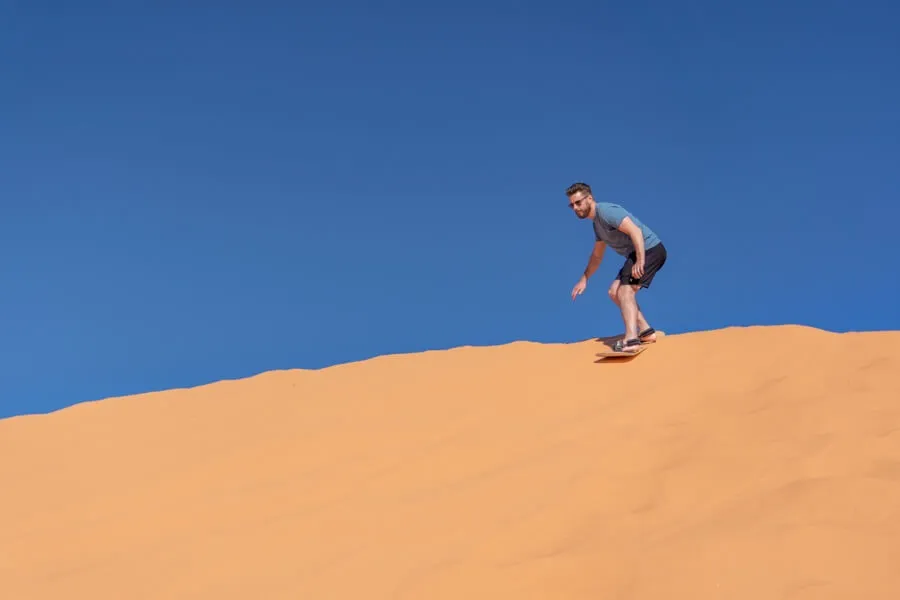 Sandboarding in Coral Pink Sand Dunes on a sunny day with blue sky near Kanab Utah