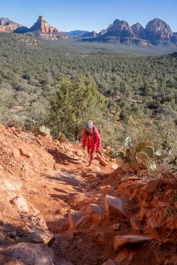 Hiker climbing a steep dirt trail in Long Canyon to the Birthing Cave in Sedona