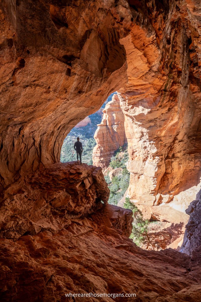 Perspective photo of a hiker stood inside a huge cave opening with light flooding inside