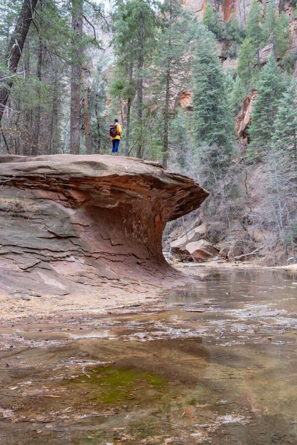 Hiker standing on top of a smooth curving rock formation above a river