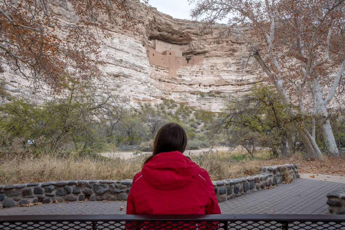 Woman looking at Montezuma Castle from park bench