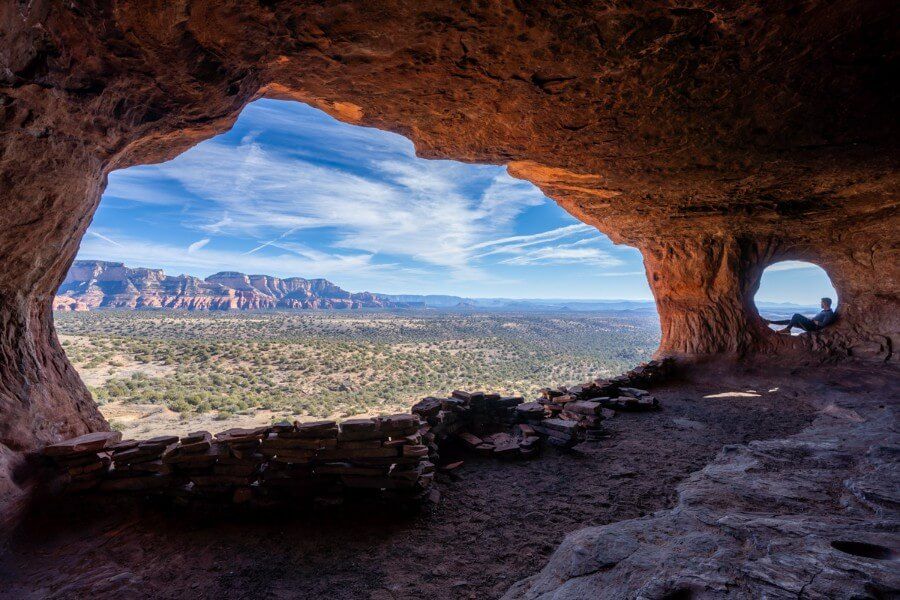 Hiker relaxing in one of the two natural windows inside Hideout Cave in Sedona Arizona