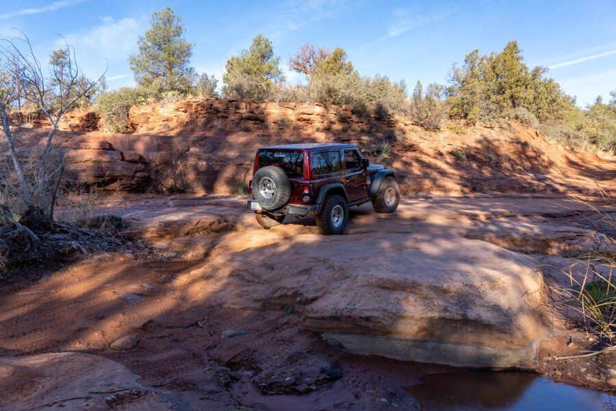 Crossing Dry Creek Basin in a maroon Jeep Rubicon covered in shadows in Sedona Arizona
