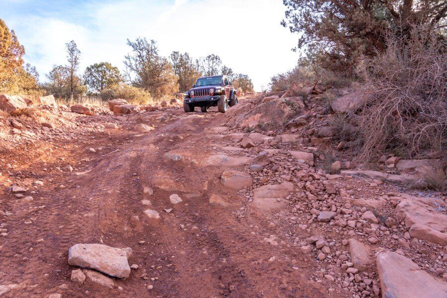 Car dropping into a ravine on a rocky road with large stones