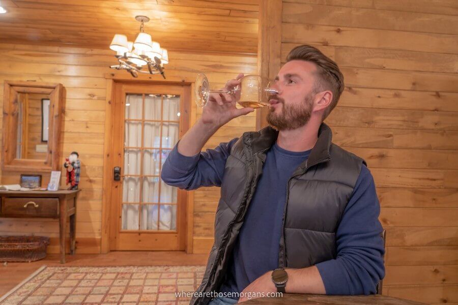 Man drinking glass of wine in a wooden building