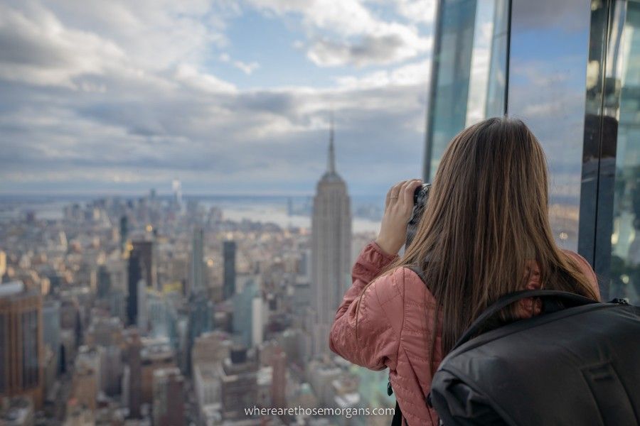 Woman taking a photo with the Empire State Building and Manhattan in the background