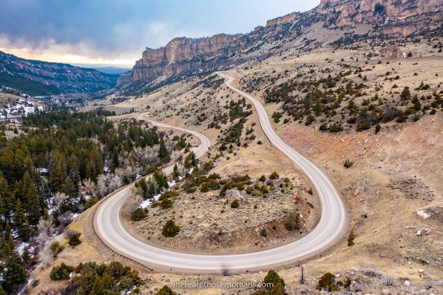 Cloud Peak Skyway scenic byway road curving in a hairpin bend with snow on the ground and trees one of the most fun things to do on a vacation to Wyoming