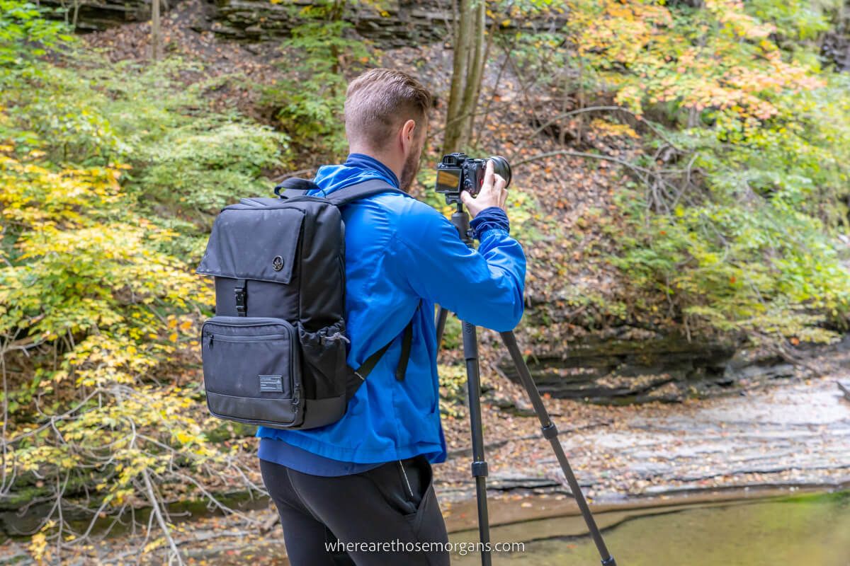 Man in a rain coat taking a photo with a tripod