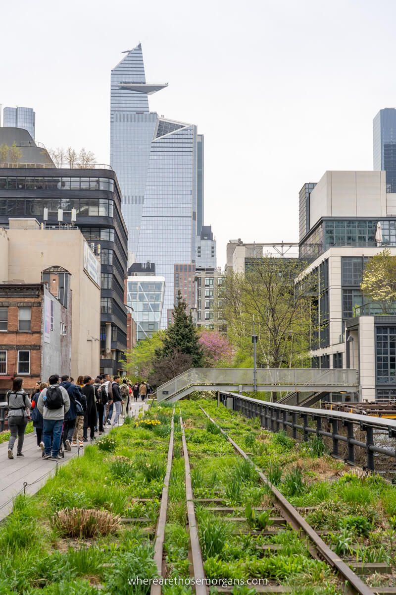 Crowd of people walking High Line next to old railway line and toward Edge at Hudson Yards