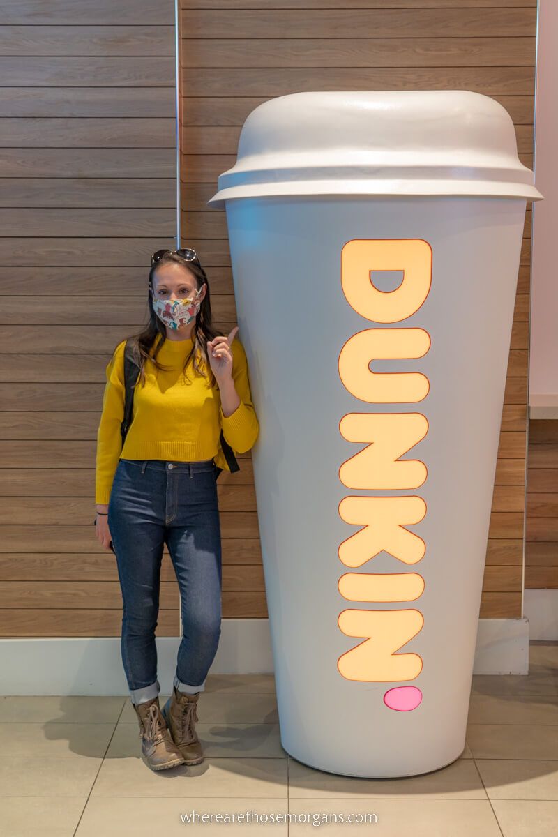Tourist stood next to life size dunkin' donuts coffee cup