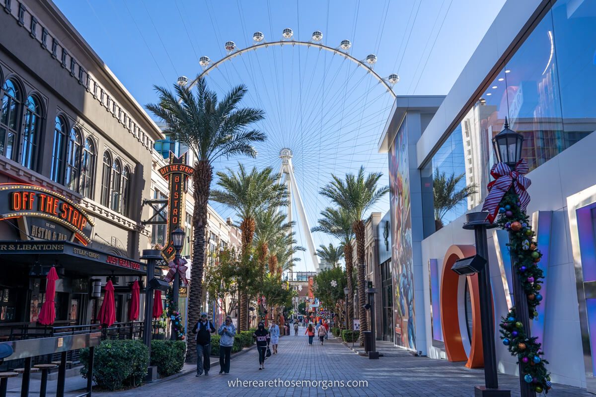 The High Roller wheel slowly turning behind row of restaurants and bars in Las Vegas in November
