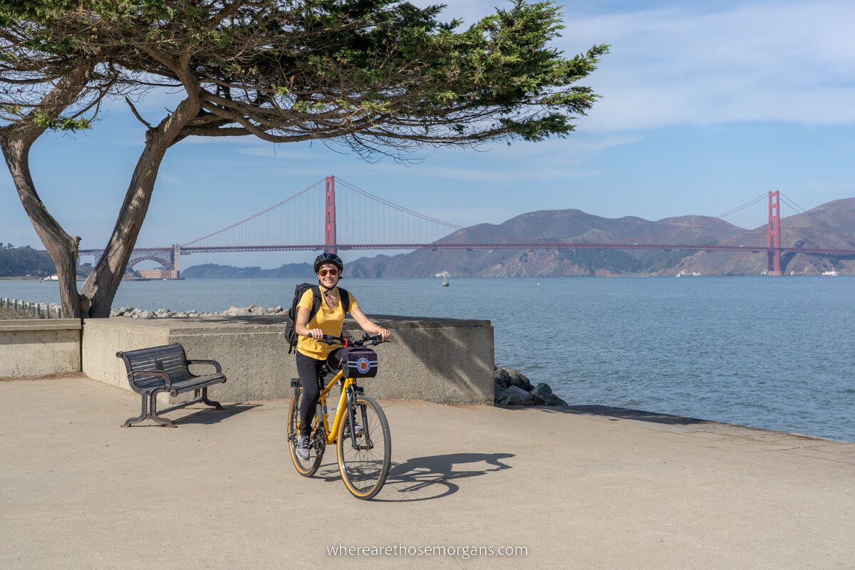 Woman posing for a photo on a bike in front of the Golden Gate Bridge
