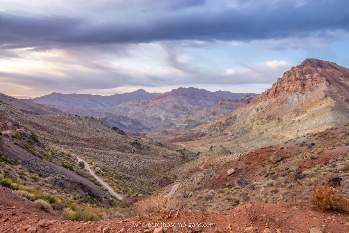 Road cutting through colorful rolling hills with a stormy sky in Death Valley