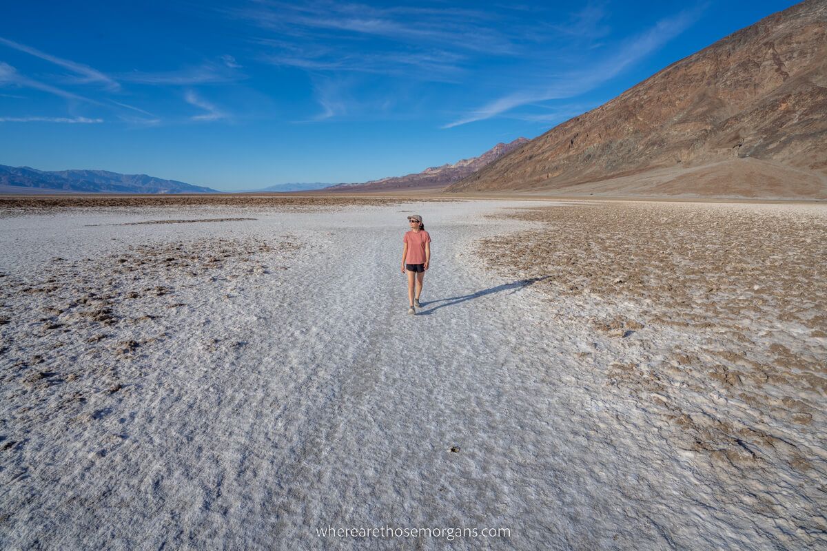 Tourist hiking alone on white salt flats in a massive flat landscape on a sunny day