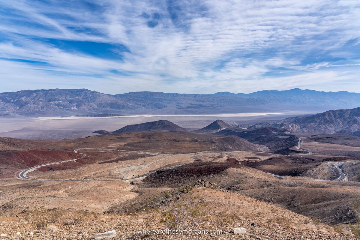 Far reaching expansive views overlooking a twisting road winding down into a vast valley floor with mountains on the far side