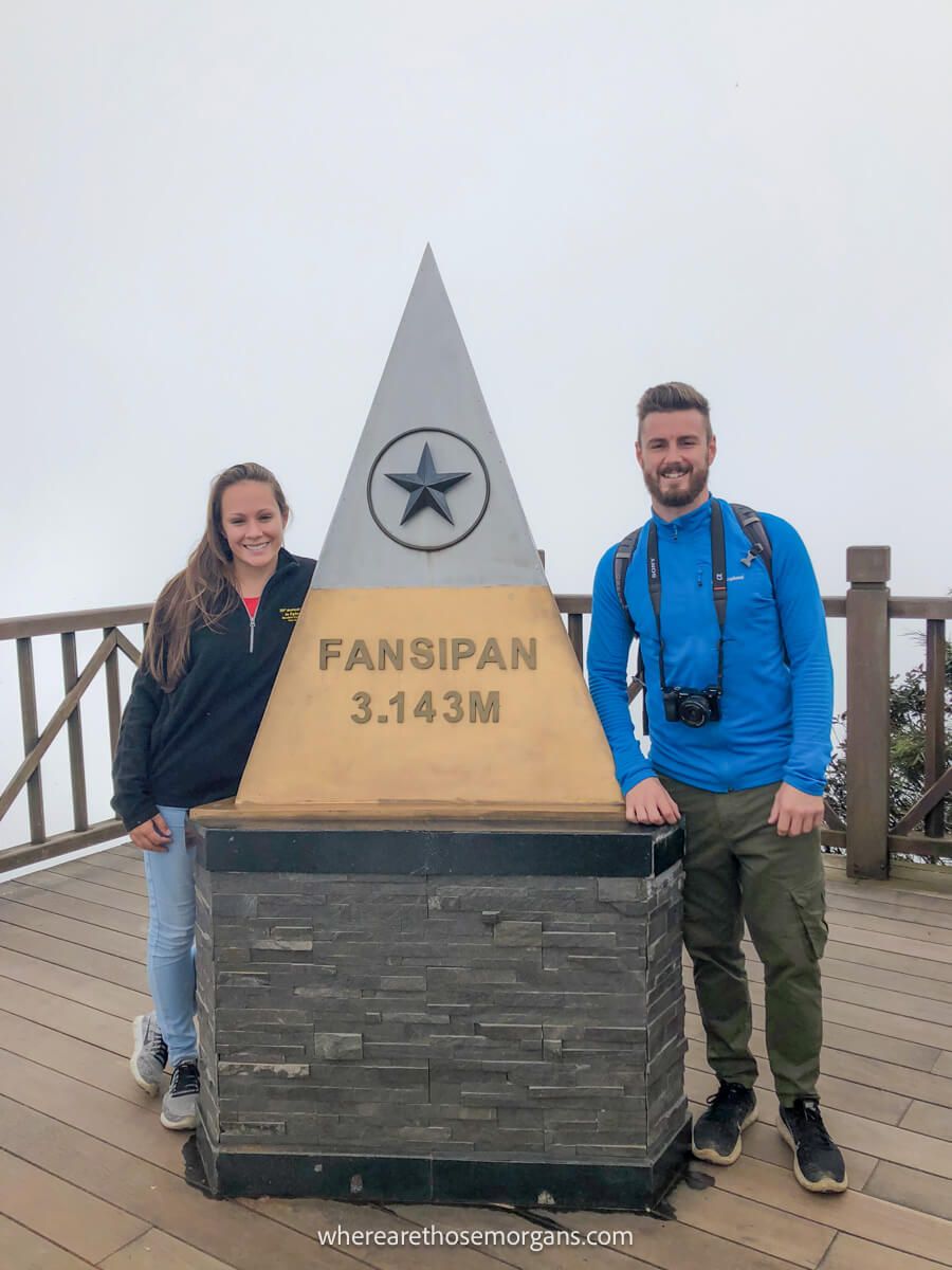 Two tourists standing at the top of the Fansipan summit in Vietnam