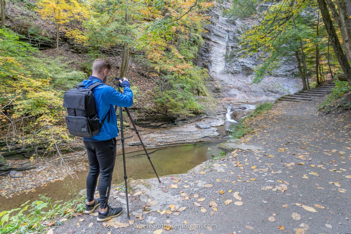 Man standing with a tripod of take a photograph of a finger lakes waterfall