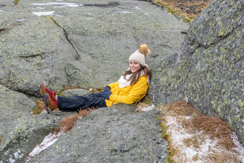 Person sitting behind a large rock to block themselves from the wind