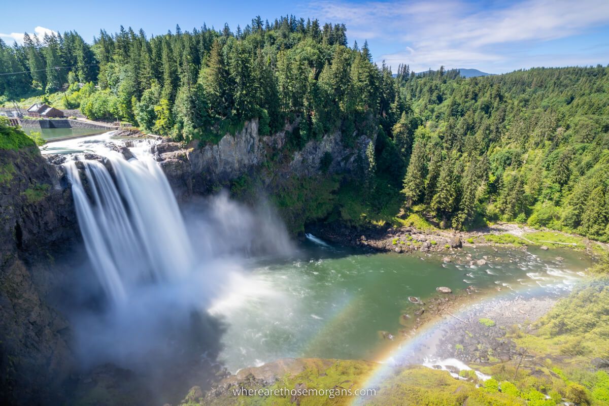 Waterfall and rainbow on a sunny day with green trees