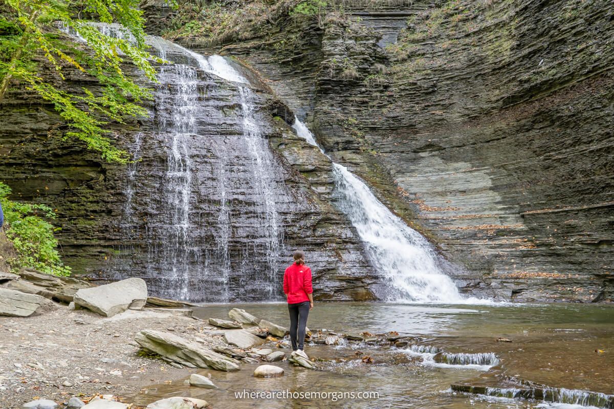 A person standing underneath large waterfall in upstate New York
