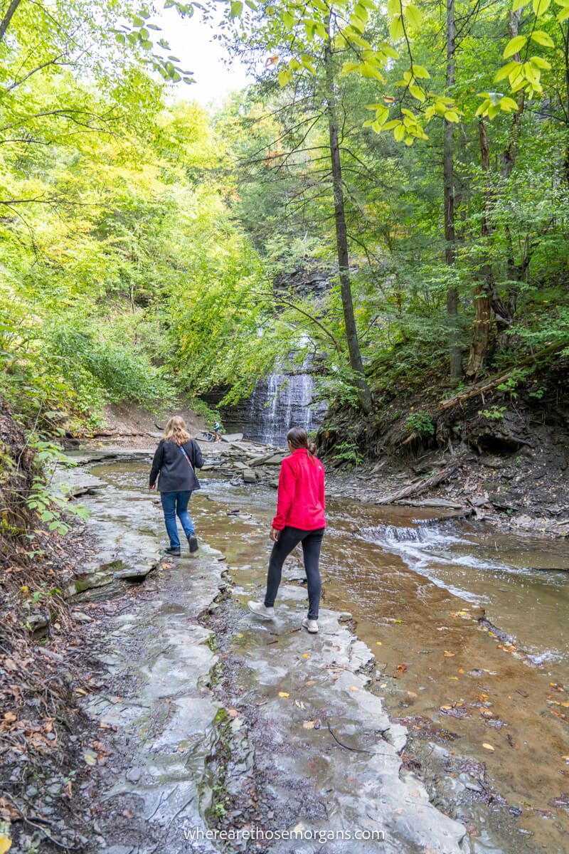 Two women walking through Grimes Glen Creek to get to the second waterfall in the park