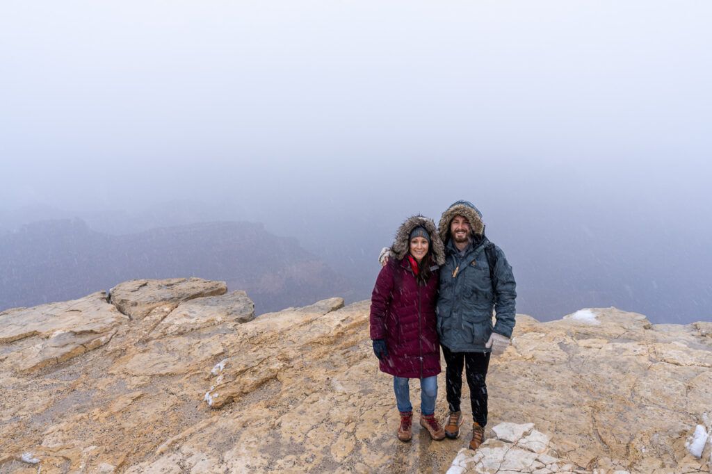 Man and woman wearing big coats at the Grand Canyon in the snow