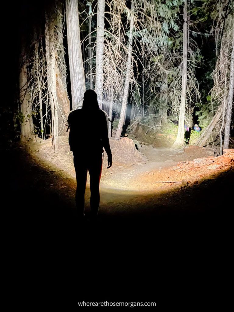 Woman walking with a headlamp to illuminate a hiking trail 