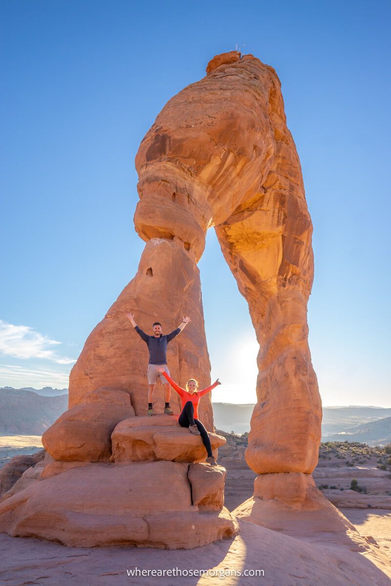 Two people taking a photo with Delicate Arches