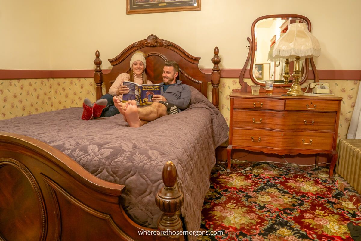 Couple laying on a bed together looking at a book