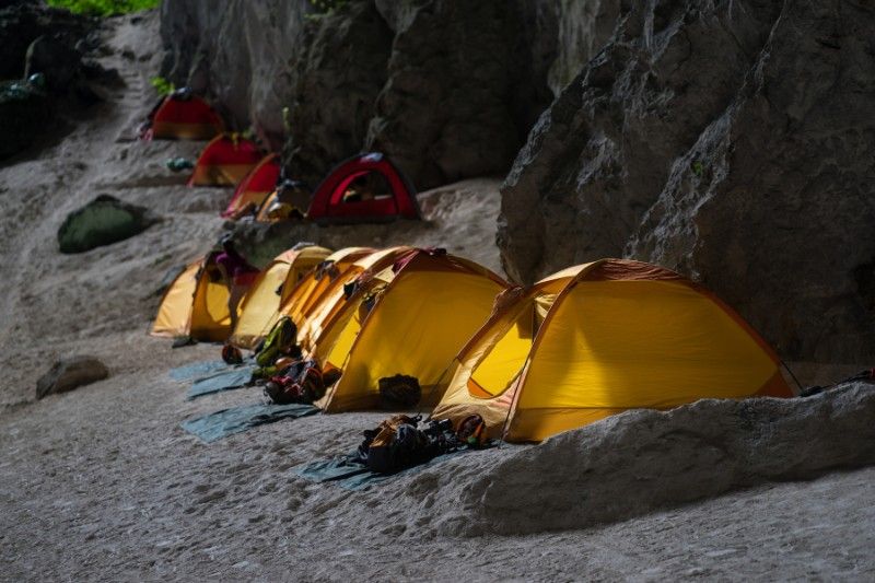 Several tents set up next to a wall inside son doong cave