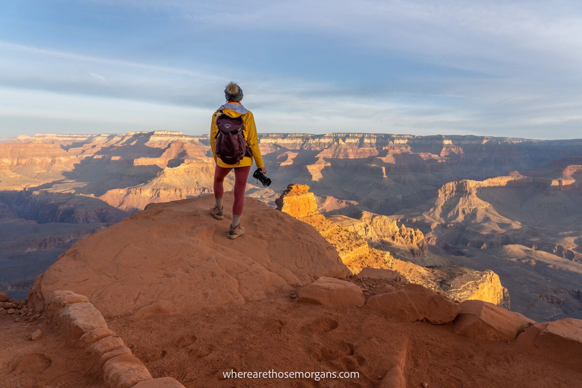 Hiker standing on the edge of a cliff overlooking Grand Canyon with camera in hand