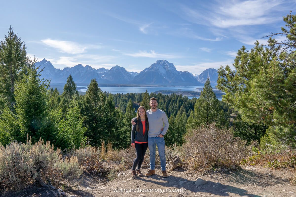 Couple standing together at Signal Mountain overlook in Grand Teton with views of trees, lakes and mountains