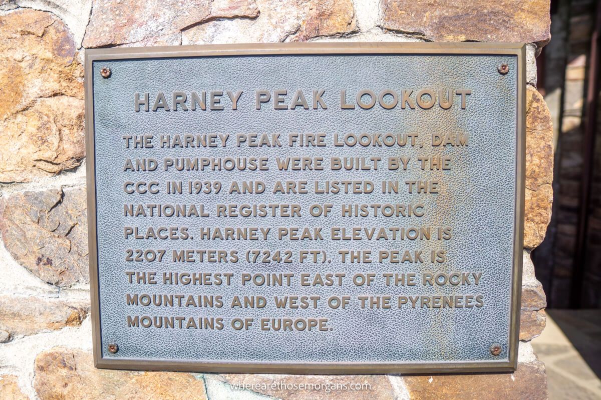 Silver colored plaque on a brick wall detailing the history of Harney Peak Lookout 