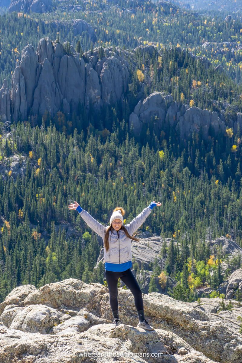 Hiker with arms raised up in the air celebrating summiting a peak in South Dakota
