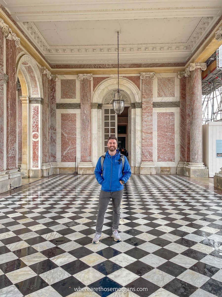 Man taking a photo with the famous pink marble columns of the Grand Trianon estate at the Palace of Vesailles