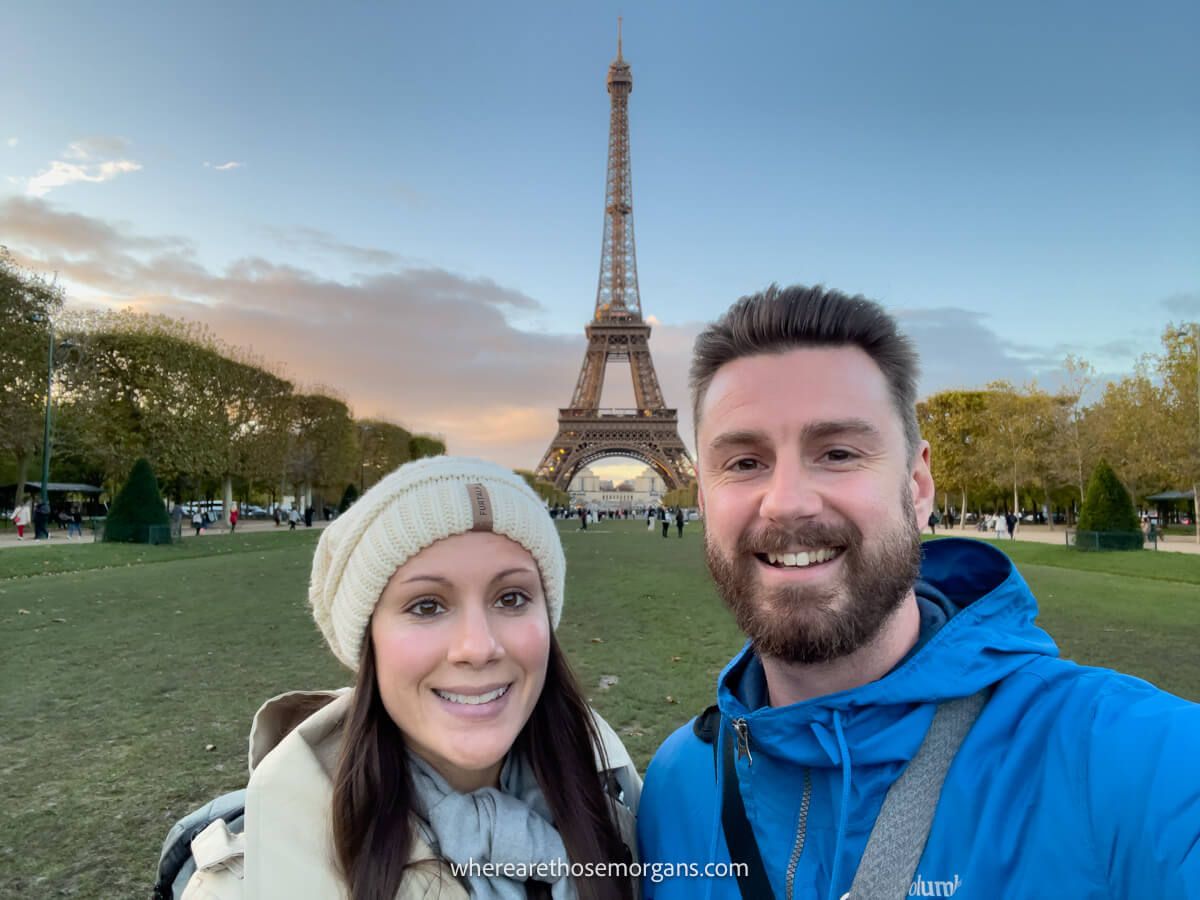 Couple taking a selfie in front of the Eiffel Tower at dusk