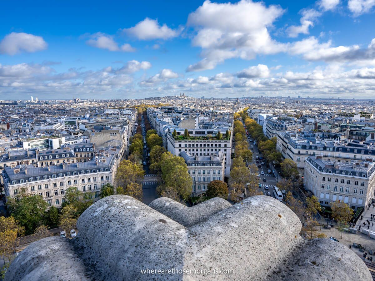 View over the streets of Paris from the top of Arc de Triomphe on a clear day with blue sky and small clouds