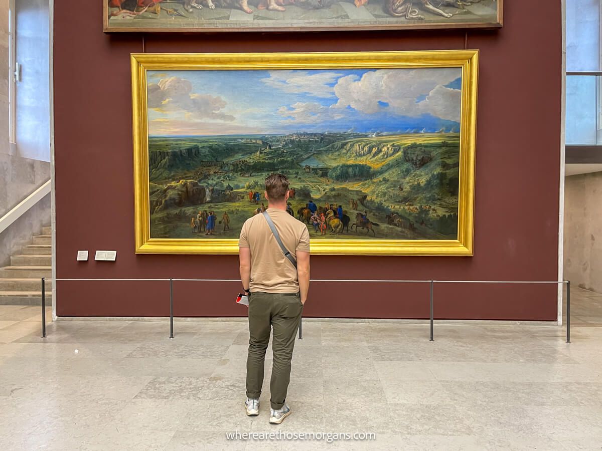 Tourist standing in front of a large painting at a Paris Museum