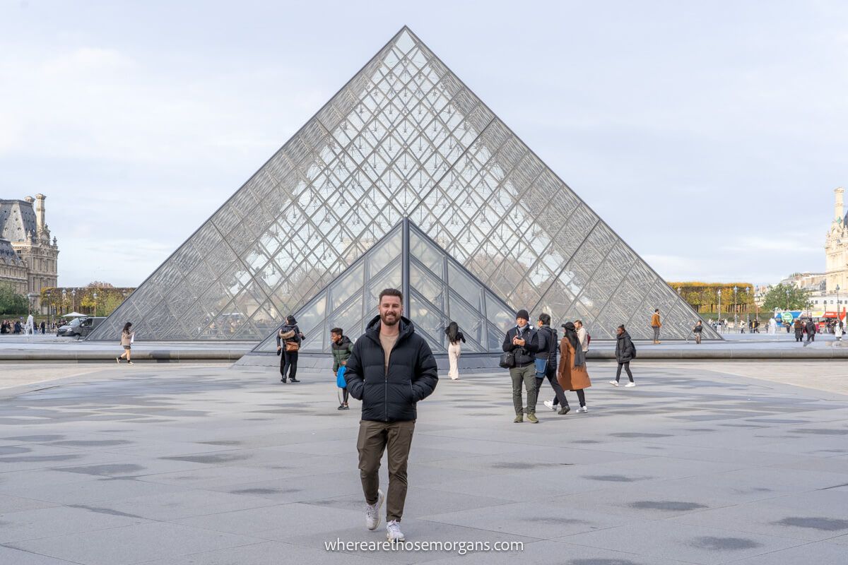 Man walking in front of the Louvre's glass pyramid