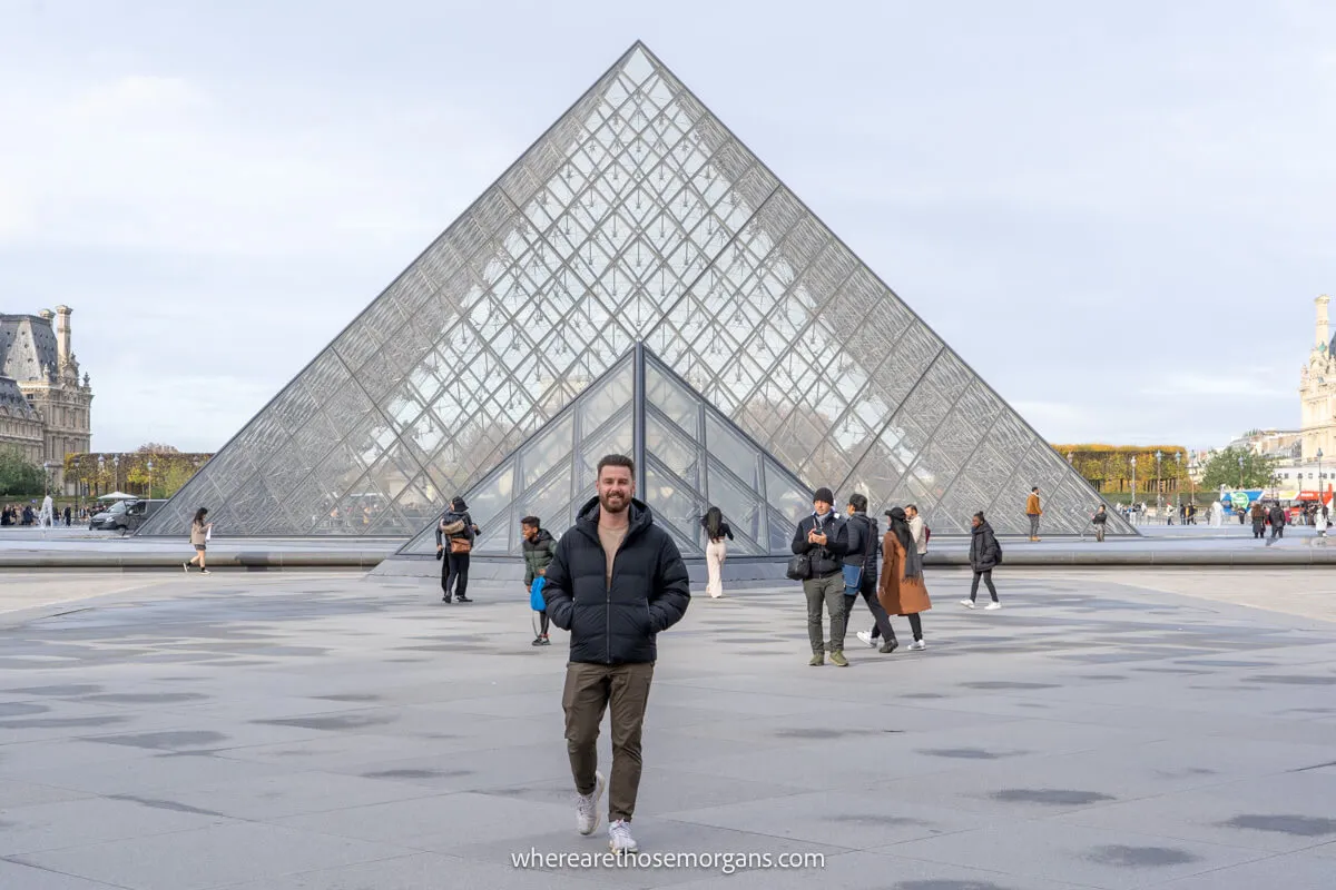 Man walking in front of the Louvre's glass pyramid