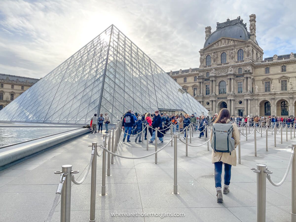 Tourist walking into the timed entry reservation line outside of the Louvre