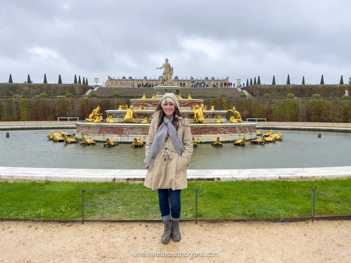Woman in a raincoat standing in the gardens of versailles