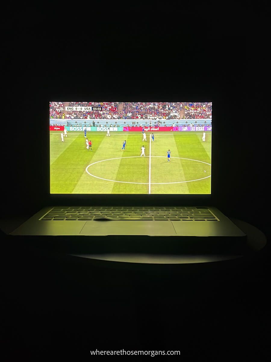 Photo of a laptop screen showing a football match with the lights off