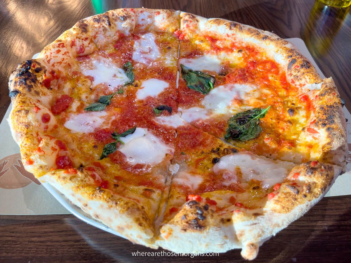 Photo of a neapolitan pizza with cheese, tomato and basil one of the benefits to long term travel is being able to eat delicious foods