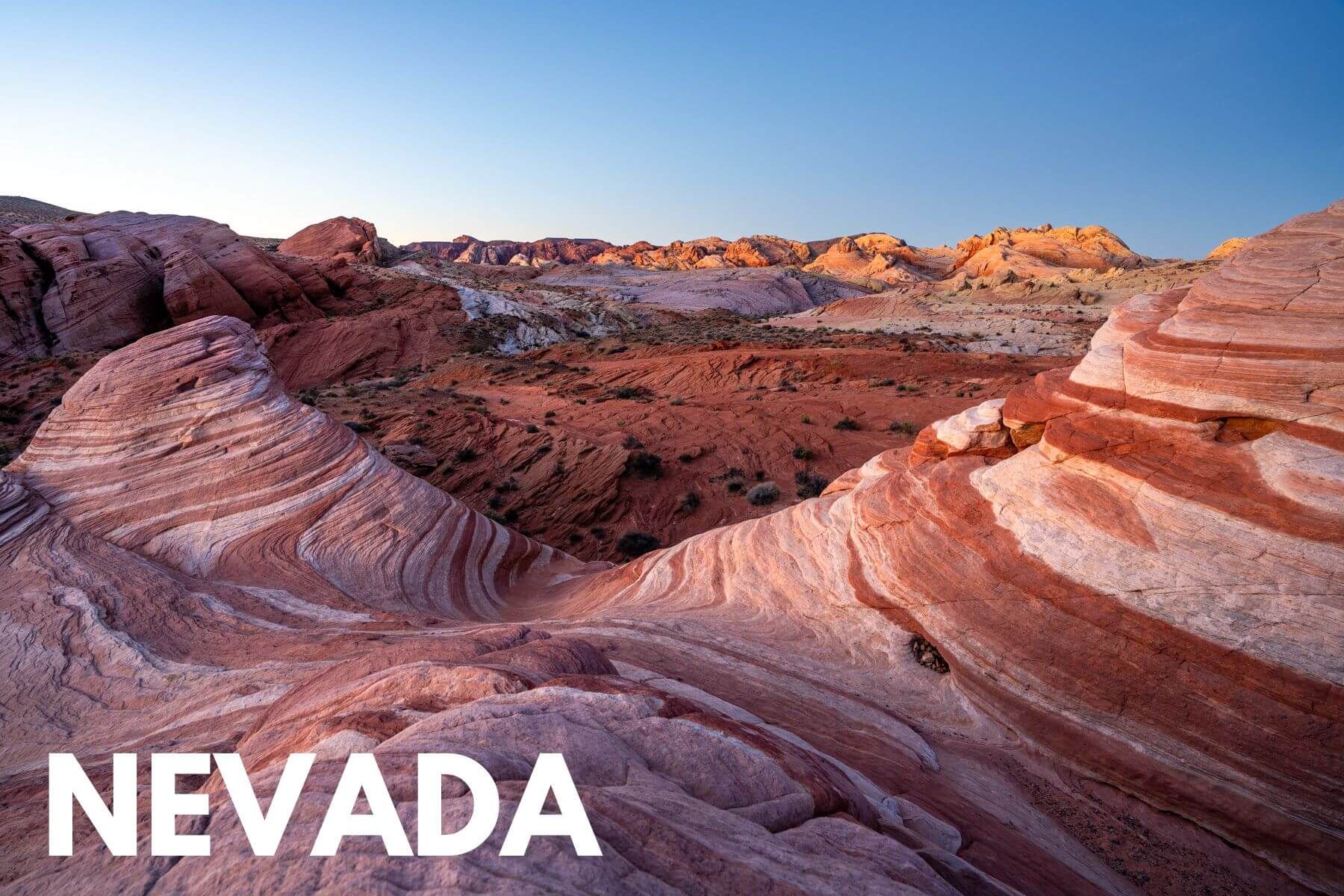 Photo of swirling rock layer patterns in a red landscape at the Fire Wave in Valley of Fire at sunrise with the word Nevada overlaid