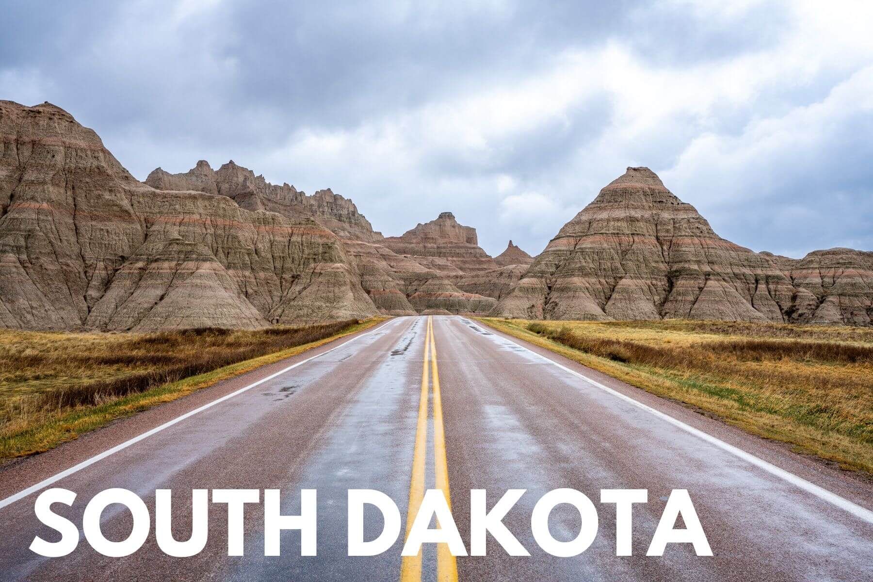 Photo of a road leading into colorful dome shaped formations in the Badlands with the words South Dakota overlaid