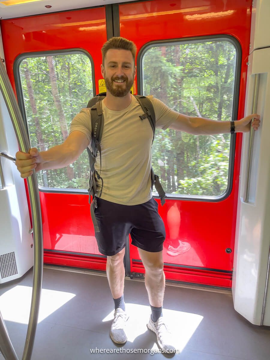 Man standing on a train in France with an Osprey backpack fully packed for a hiking trip