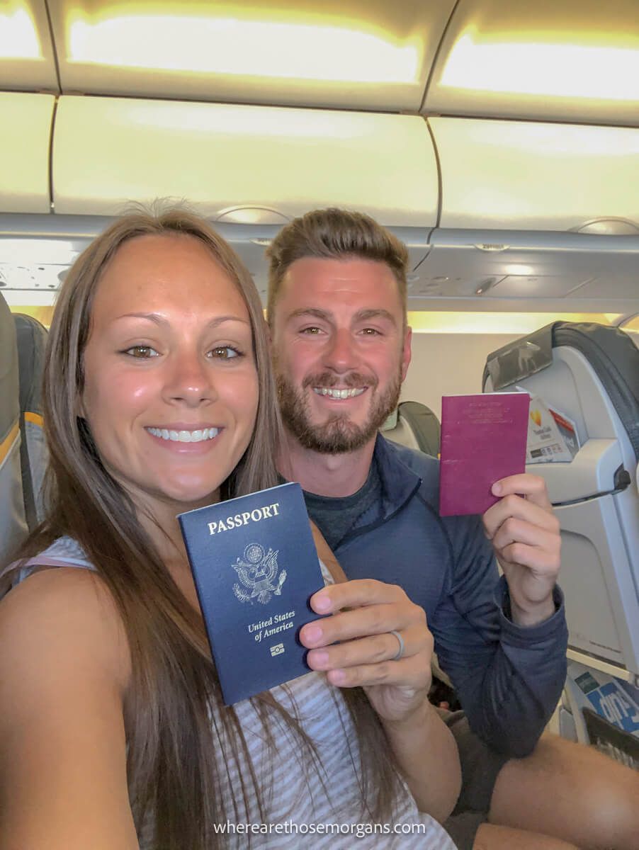 Two people holding their passports on a plane